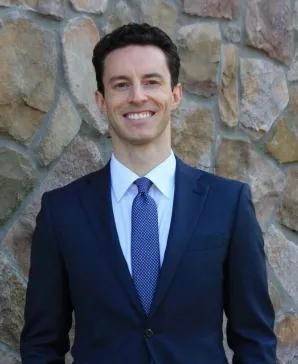 Tyler Gallaway, smiling, wearing a blue suit and tie