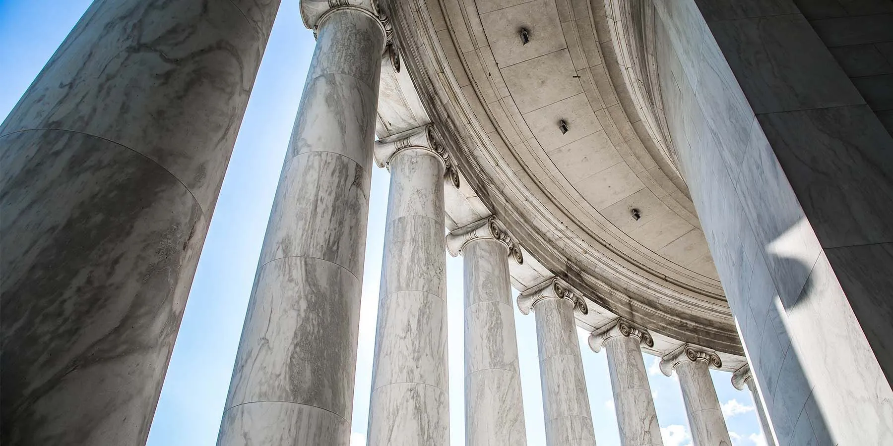 Looking up at the columns of a building with a blue sky in the background.